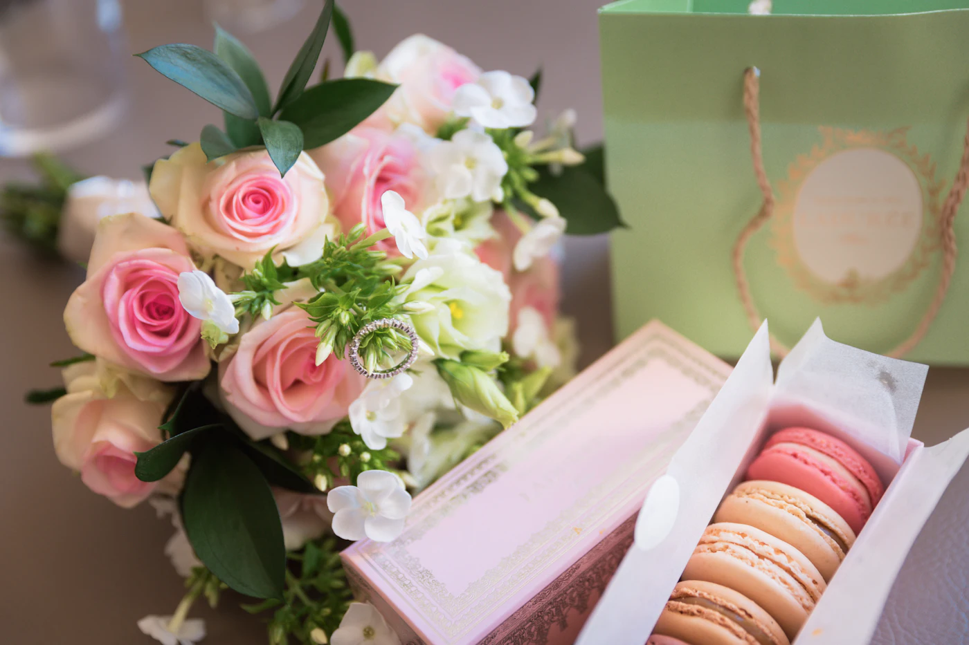 Buchet de trandafiri roz lângă o cutie cu macarons.